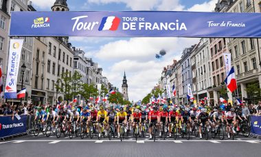 Cyclists lined up at Tour de Francia 2025 starting line with banners and crowds