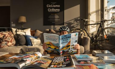 Cyclist reading cycling book in living room with inspirational cycling poster