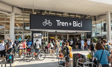 Travelers with bikes at Spanish train station showing Tren + Bici signage