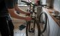 Un ciclista pone a punto los frenos de su bicicleta en la cocina de casa.