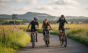 Un grupo de ciclistas pedaleando juntos por una carretera rural rodeada de paisajes espectaculares.